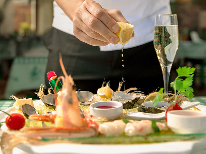 A waiter squeezes lemon over oysters as part of the seafood grill offered to guests at Manos restaurant at D Maris Bay.