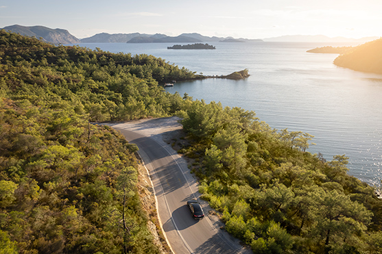 A chauffeur drives a scenic route  along the coast as he provides a transfer serive for guests.   Vews are of the beautiful ocean and distant mountains on the outskirts of the D Maris Bay resort. 