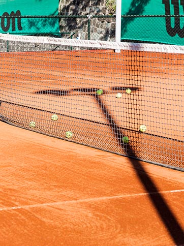 A close up of the astro turf surface, net and balls on the tennis courts that are part of the wellness and leisure facilities at D Maris Bay resort.